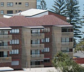 A multi-story building with balconies, a brick facade, and a flat roof.