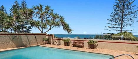 A swimming pool with a view of the ocean and palm trees.
