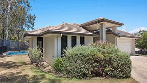 A residential house with a covered patio, a swimming pool, and a well-maintained garden. - 4BR Pool Hideaway Near Beach (Moffat Beach)