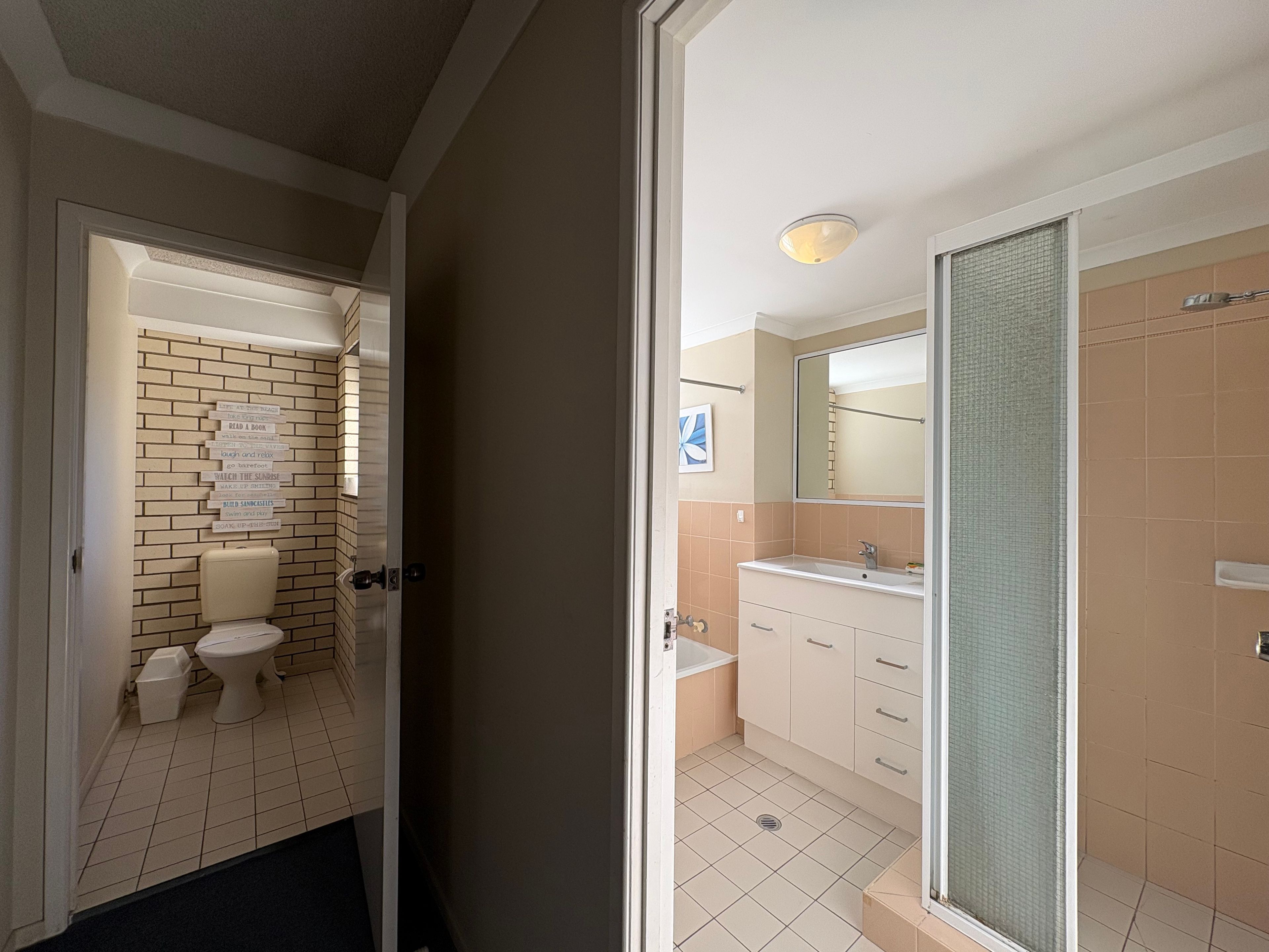 A bathroom with a toilet, sink, and shower area.