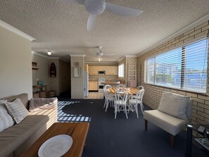 A compact living space with a kitchenette, dining area, and seating. - Whiteopal Close To Kings Beach With Ocean Views (Kings Beach)