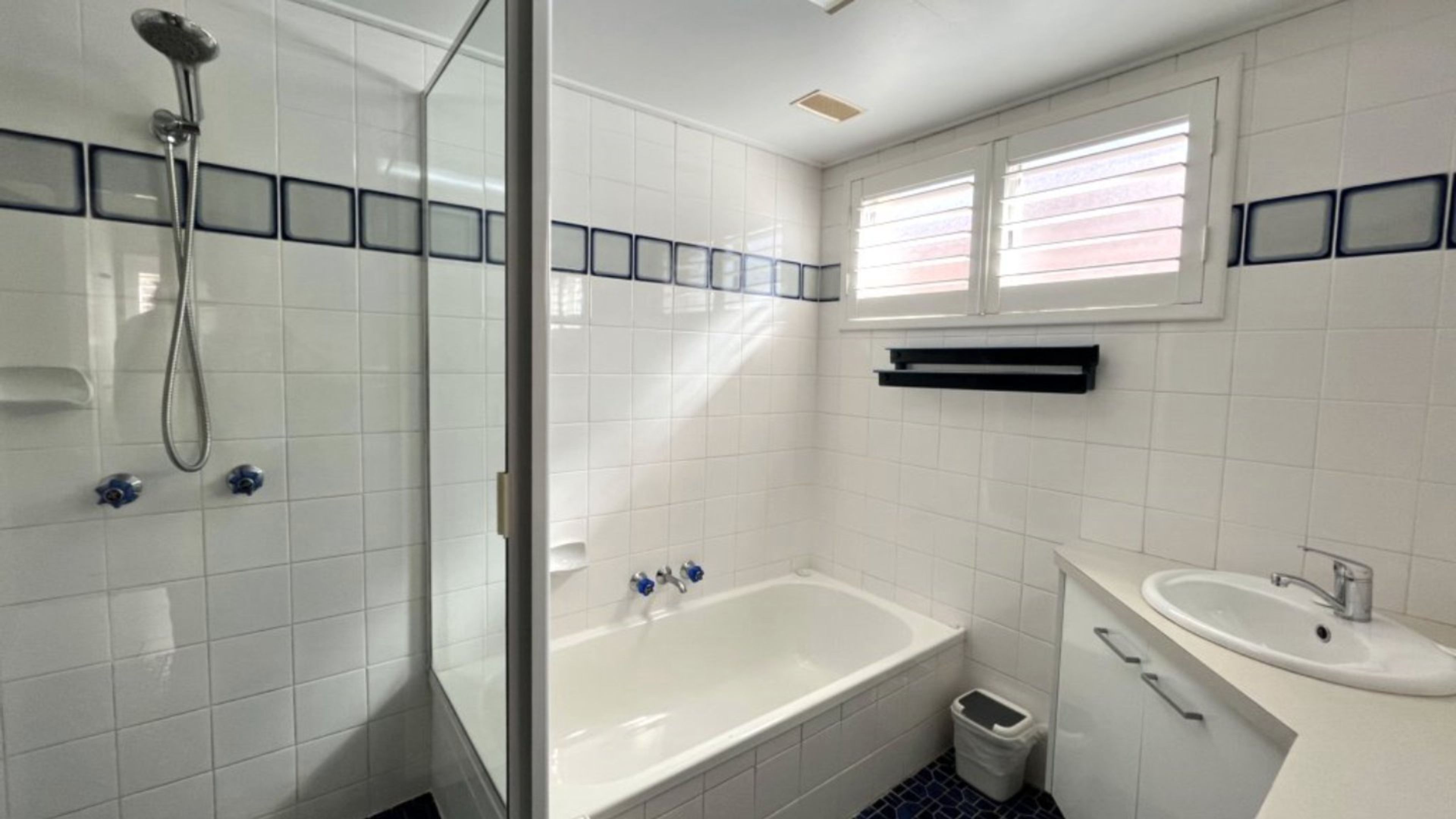 Een badkamer met een douche, een bad, een wastafel en een raam.