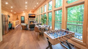Una cabaña espaciosa de madera con cocina, comedor y una mesa de futbolín.