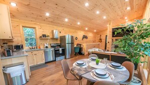 Una cocina moderna con armarios de madera, electrodomésticos de acero inoxidable y un comedor con una mesa dispuesta para cuatro.