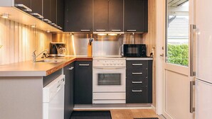 A compact kitchen with dark cabinets, a stainless steel range, a microwave, and a dishwasher. - 6 Person Holiday Home in Otterup (Otterup)