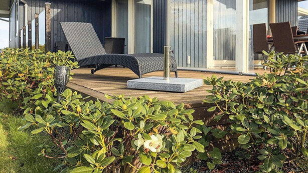 A modern outdoor seating area with a lounge chair, a small table, and a decorative lamp. - 6 Person Holiday Home in Otterup (Otterup)
