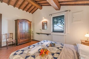 A bedroom with a bed, a wardrobe, a chair, a window with a view, and a radiator.