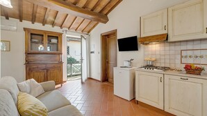 A compact kitchen with wooden cabinets, a built-in stove, and a small refrigerator. - Chianti Olmo&Pini Shared Pool, Castelfiorentino, Italy (Castelfiorentino)