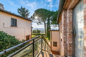 A residential property with a balcony, a view of the countryside, and a large tree. - Chianti Apt Olmo&Pini Shared Pool, Castelfiorentino, Italy (Castelfiorentino)