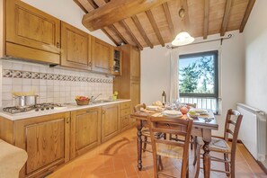 A kitchen with wooden cabinets, a tiled backsplash, a stove, and a dining table set for four.