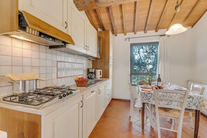 A kitchen with a gas stove, white cabinets, and a dining area with a table and chairs.