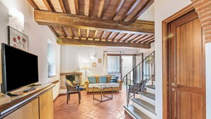 A living room with a TV, sofa, and coffee table. There is a staircase leading to another level. - Chianti Site Fienile Shared Pool, Castelfiorentino, Italy (Castelfiorentino)