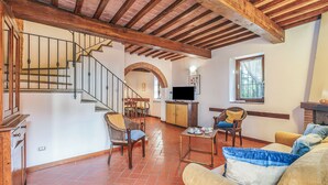 A spacious living area with a wooden staircase, a fireplace, and a television. - Chianti Site Fienile Shared Pool, Castelfiorentino, Italy (Castelfiorentino)