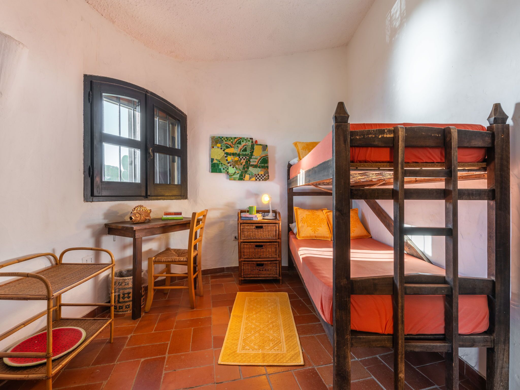 Una camera accogliente con un letto a castello, una scrivania con sedia, un tavolino e una finestra.