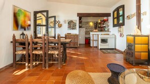 Un salón acogedor con una mesa de comedor de madera y sillas, una cocina con estufa y armarios, y un ventanal grande.