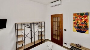 A bedroom with a wooden bed, a wardrobe with a mirror, a door, and a wall-mounted air conditioner. - Arsenale Suites, Family Comfort. Perfect for families or friends to relax (Torino)