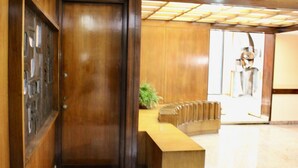 A wooden reception desk with a plant, a door, and a view of a room with a chair. - Arsenale Suites, Family Comfort. Perfect for families or friends to relax (Torino)