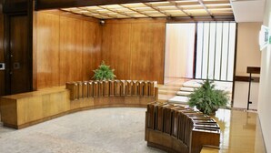 A reception area with a curved wooden desk, a potted plant, and a staircase in the background. - Arsenale Suites, Family Comfort. Perfect for families or friends to relax (Torino)