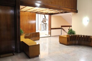 A reception area with a wooden reception desk, a staircase, and a view of a sculpture. - Arsenale Suites, Family Comfort. Perfect for families or friends to relax (Torino)