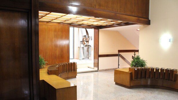 A reception area with a wooden reception desk, a staircase, and a view of a sculpture. - Arsenale Suites, Love Nest. A cozy retreat for two, where romance meets comfort (Torino)