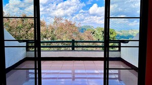 Une pièce dotée d’une grande fenêtre donnant sur un paysage montagneux, avec des arbres et un ciel dégagé.