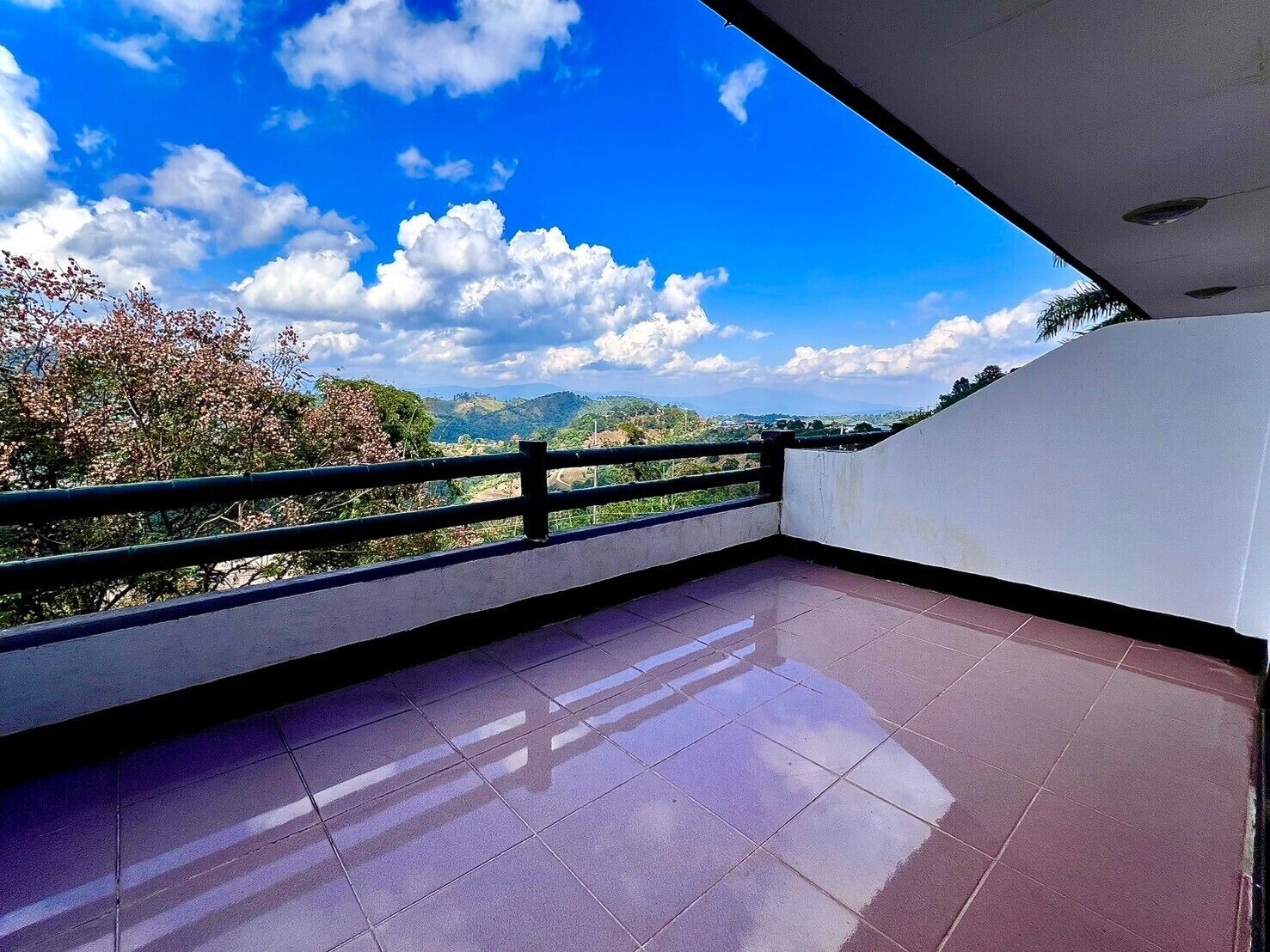A balcony with a clear view of the sky and distant hills.