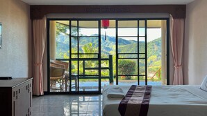 Une chambre d’hôtel équipée d’un lit, d’un bureau et offrant une vue sur un paysage montagneux grâce à de grandes fenêtres.