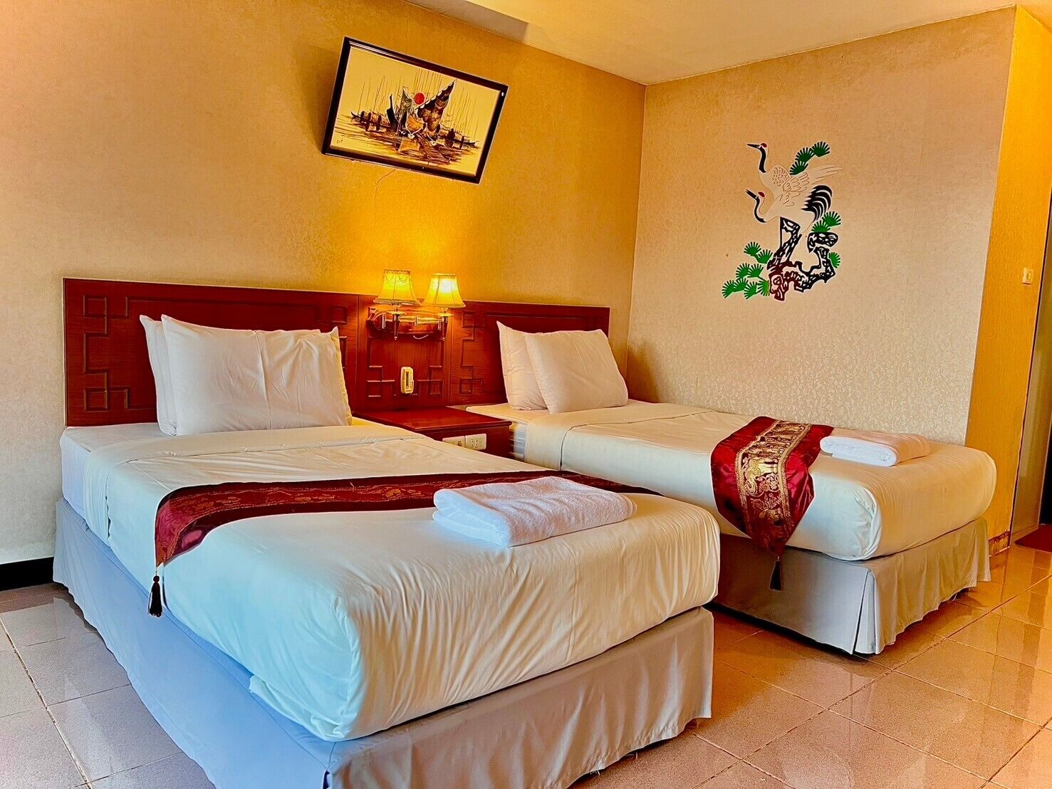 Habitación de hotel con dos camas, cabecero de madera, una obra de arte colgada en la pared y diseño decorativo en la pared.