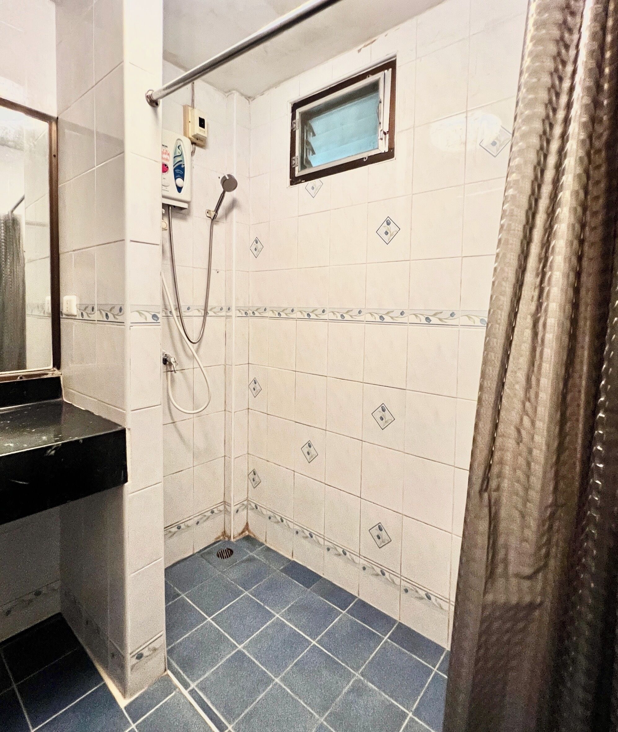 Un baño pequeño con ducha, lavamanos y ventana.