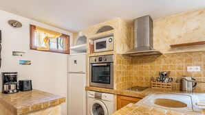 A compact kitchen with a washing machine, a microwave, and a built-in oven.
