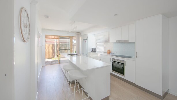 A modern kitchen with white cabinetry, a central island, and a built-in oven.