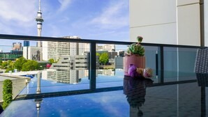 Une chambre d’hôtel moderne avec un balcon en verre, une vue sur la ville et une plante en pot.