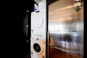 A compact kitchen with a stainless steel refrigerator and a washing machine. - SugarTree Two Bedrooms Apartment (Auckland)