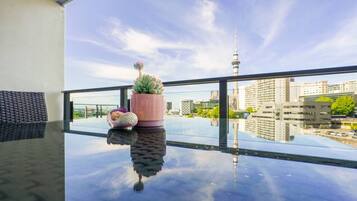 A balcony with a glass table, a pink pot with a succulent, and a decorative item resembling a bird.