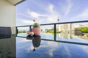 Ein Balkon mit einem Glastisch, einem rosa Topf mit einer Sukkulente und einem dekorativen Vogel-Ornament.