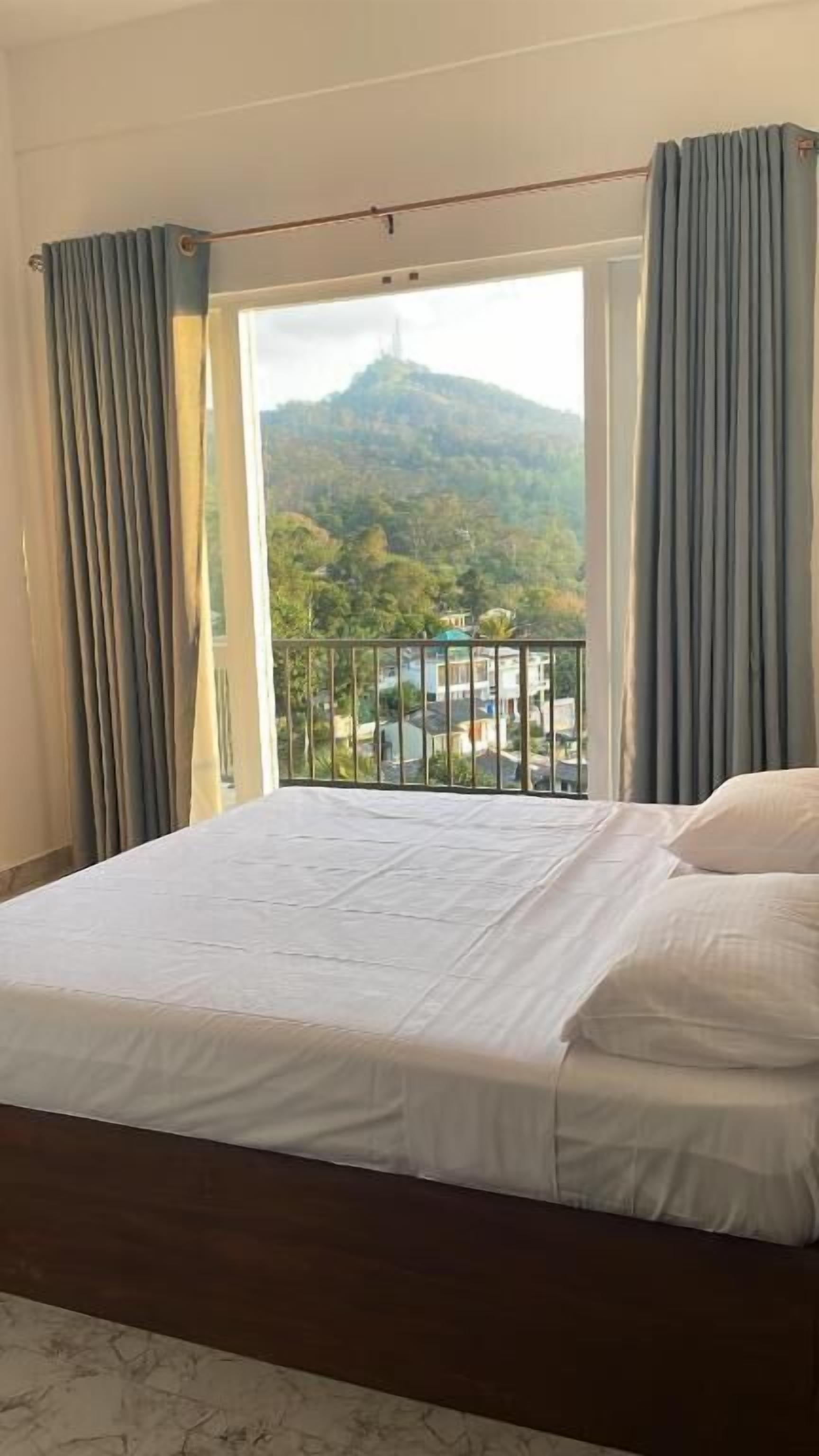 Ein Schlafzimmer mit Bett, Vorhängen und Blick auf eine Berglandschaft.