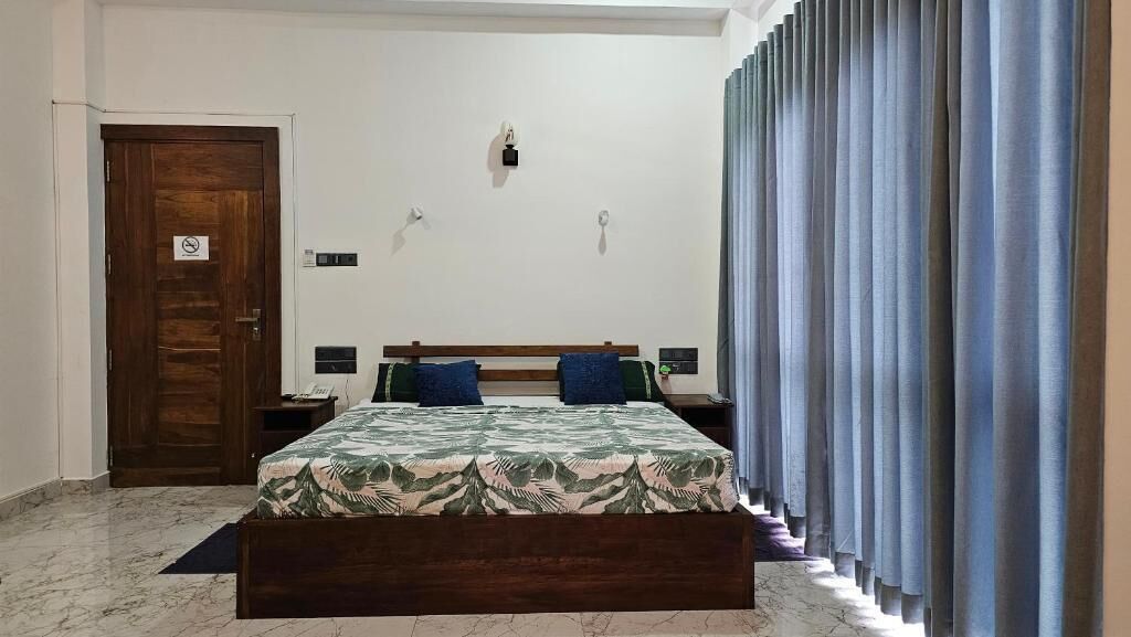 Un dormitorio con una cama de madera, dos mesitas de noche, una lámpara de pared y una puerta con letrero de no fumar.