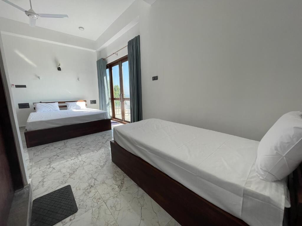 A hotel room with two beds, a ceiling fan, and a large window with curtains.