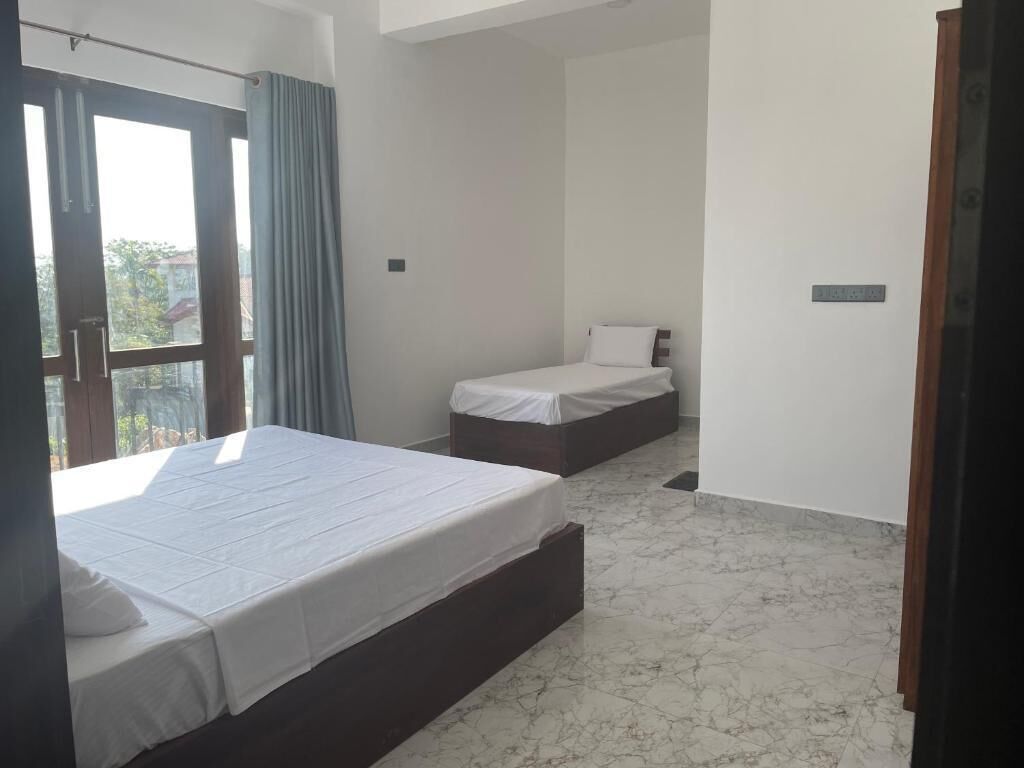 Une chambre d’hôtel avec un grand lit, un lit plus petit et une fenêtre avec des rideaux.