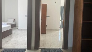 Una camera d'albergo con un letto, una porta in legno e vista su un'altra stanza.