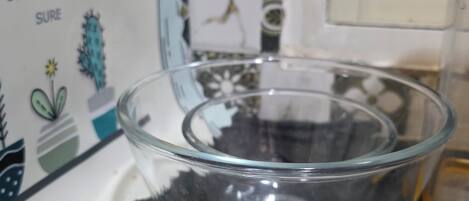 A clear glass bowl on a dark countertop, with a decorative box in the background featuring a cactus and text.
