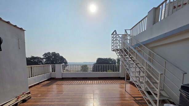 A rooftop terrace with a wooden floor, a metal staircase, and a white railing. - Narayans Residency (Gaya)