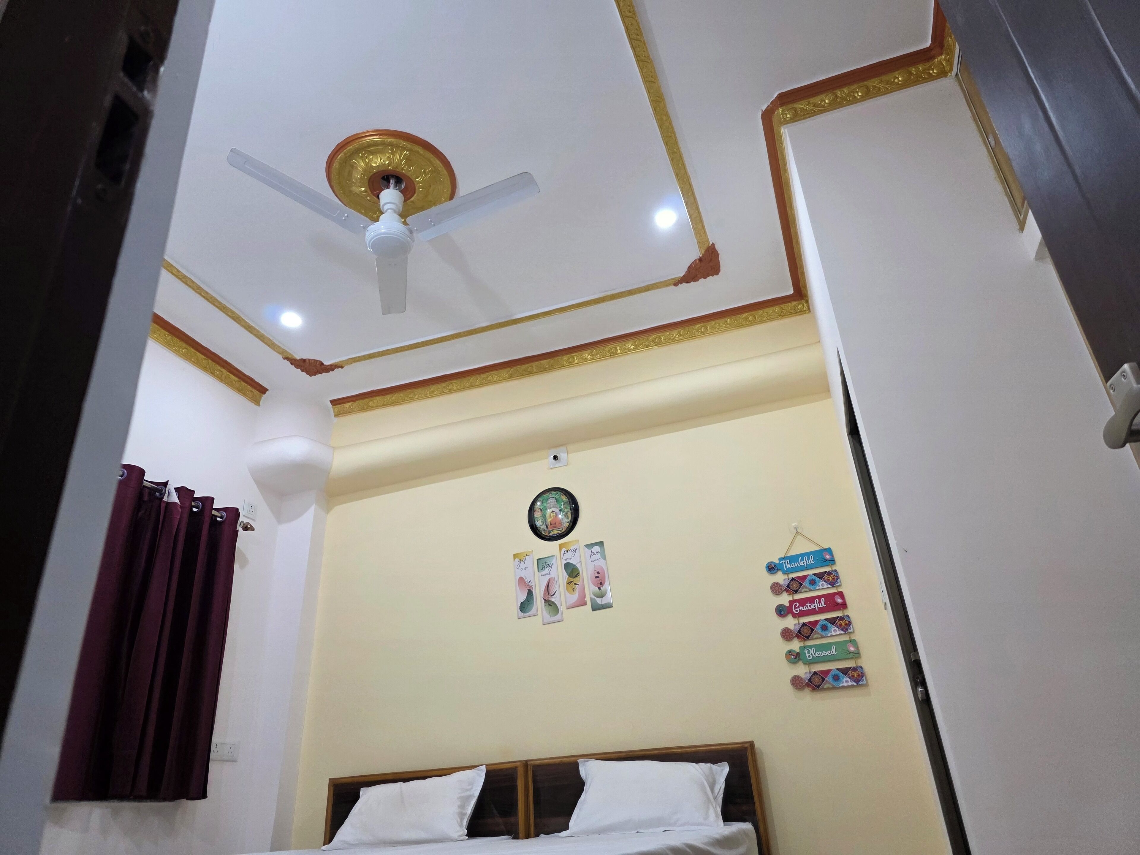 A bedroom with a bed, a ceiling fan, and a wall with motivational posters.