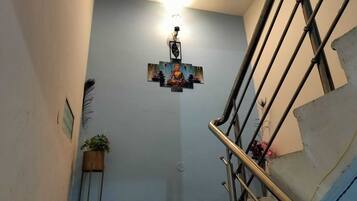 A staircase with a handrail, a wall-mounted light fixture, and a Buddha statue.