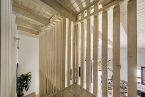 A modern interior with wooden slats, a potted plant, and a view of the outdoors.