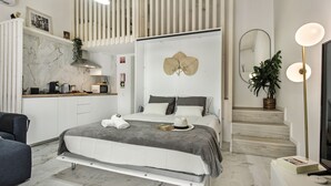 Une chambre moderne dotée d’un grand lit, d’un bureau intégré et d’un escalier menant à un niveau supérieur.