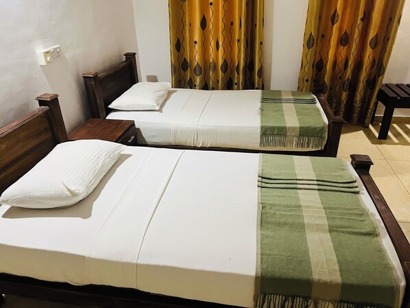 Two single beds with white bedding and a green and beige blanket, wooden headboards, and a small wooden table. - Kingfisher Resort & Retreat Sigiriya (Sigiriya)