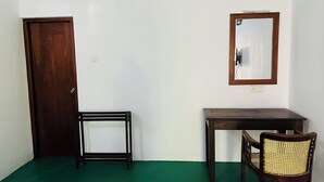 Une pièce avec une porte en bois, une petite table, une chaise et un miroir au mur.