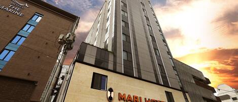 A business hotel with a prominent sign, a parking sign, and a tall adjacent building.