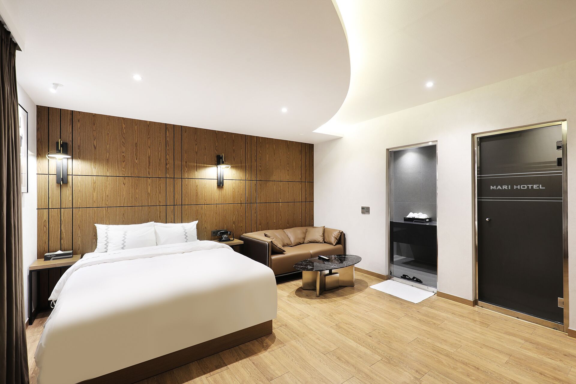 Ein modernes Hotelzimmer mit einem großen Bett, einer Couch, einem kleinen Couchtisch und einem Kleiderschrank.
